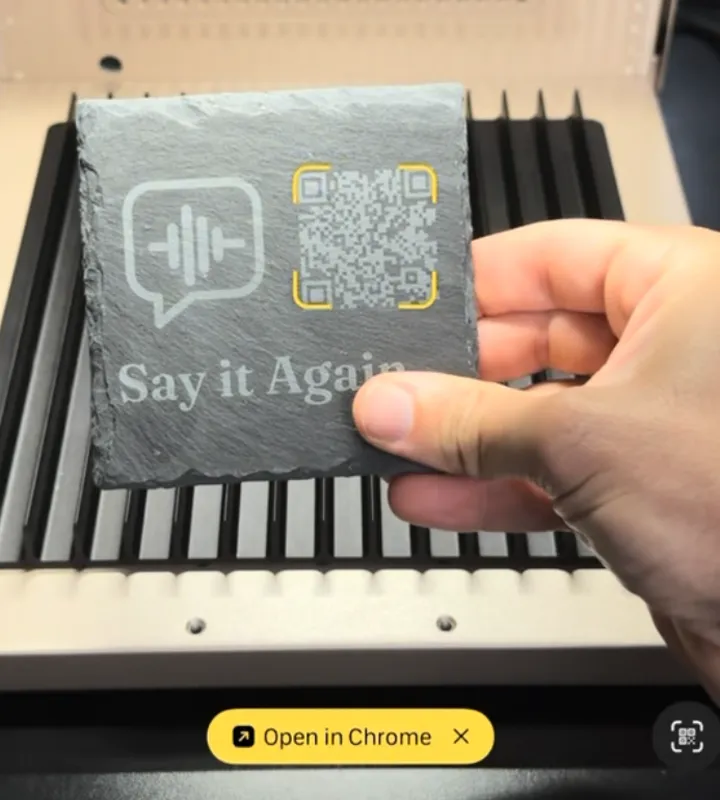 The owner’s engraved slate with its QR code and a phone camera’s scan prompt.